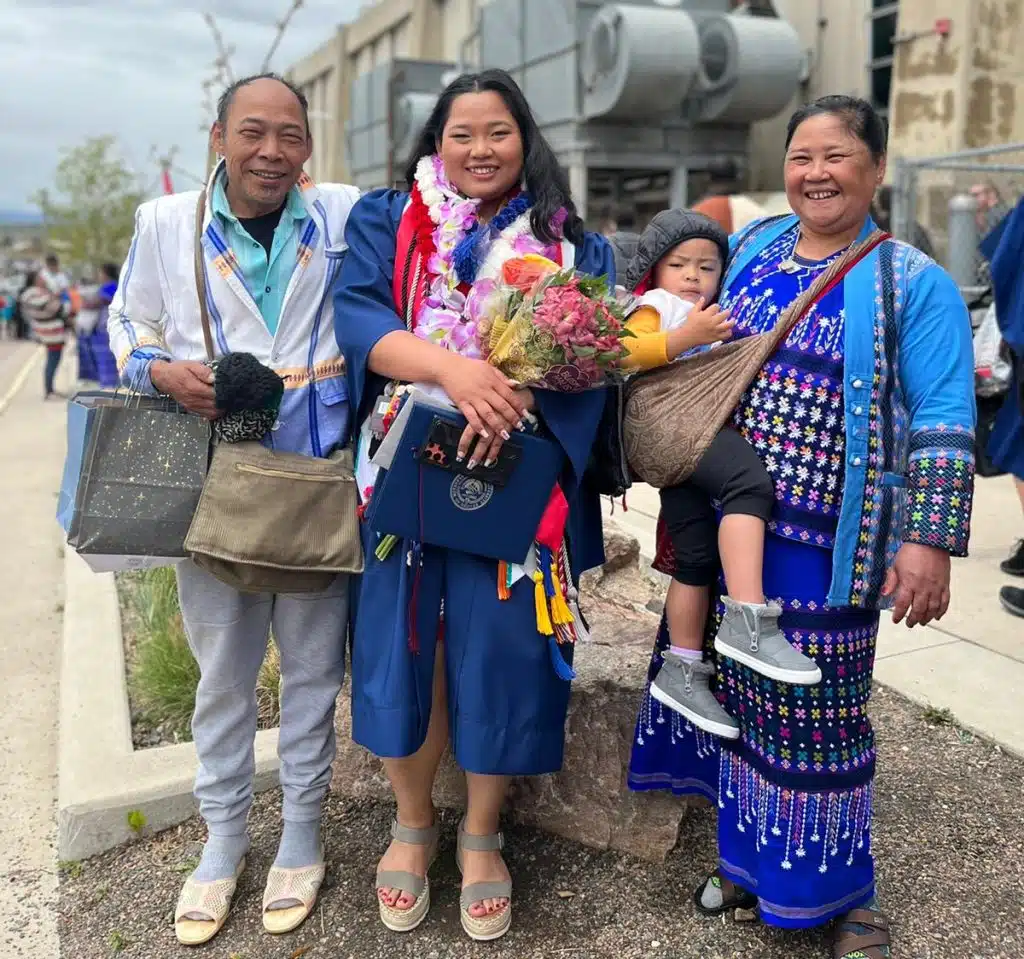 Redar Moo standing with her family—father, mother, and other loved ones—outdoors on campus, all smiling proudly
