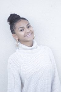 Mary poses in a white turtleneck against a blank background